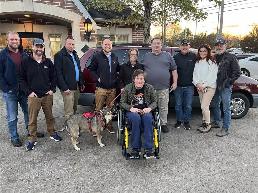 The Mechanics on a Mission volunteer team with a neighbor receiving a donated vehicle